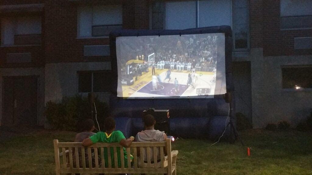 Guests watching a movie on an inflatable outdoor movie screen at a Rolling Video Games event
