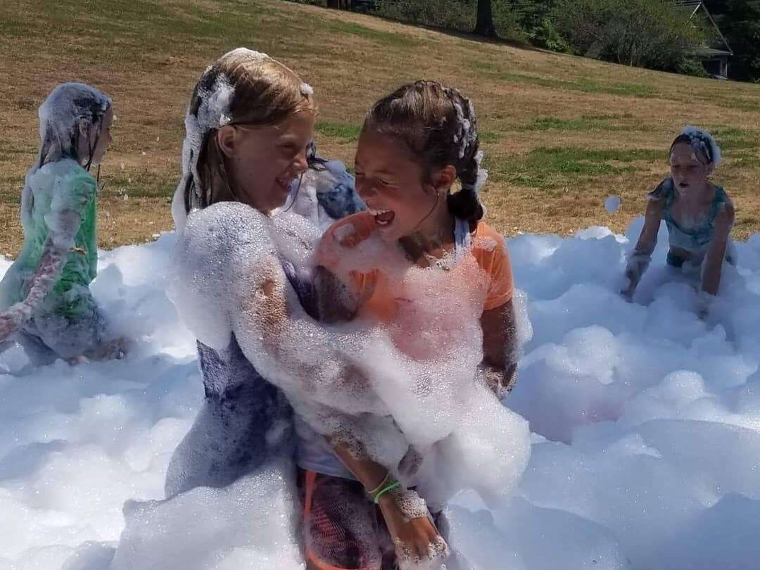 Kids having fun in a pile of foam at a foam machine party.