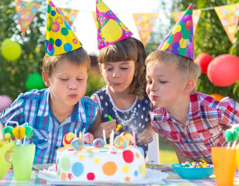 Kids blowing out birthday cake candles during a party